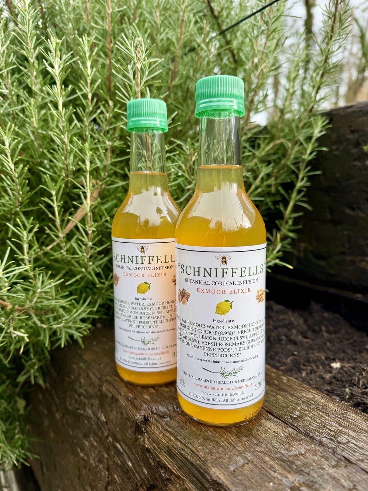 Two bottles of Schniffells on an old timber sleeper beside rosemary
